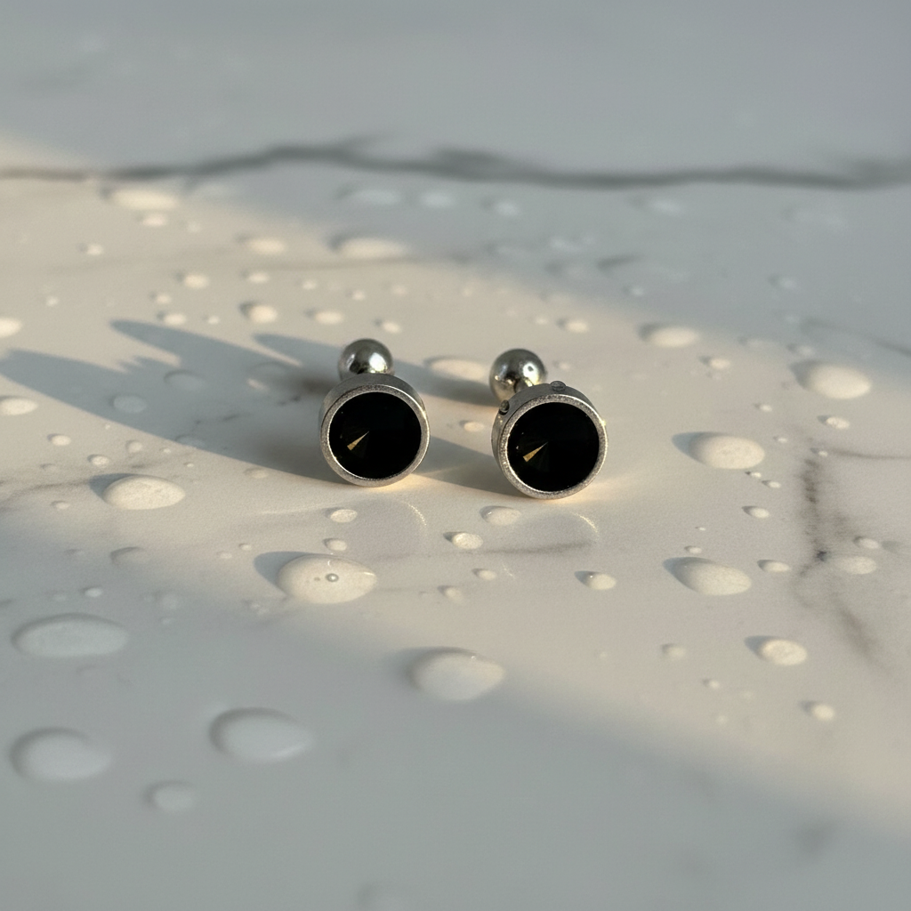 Silver 925 earrings on wet marble with golden light
